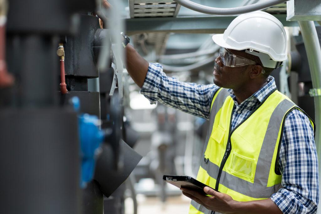 Male plumber engineer working at sewer pipes area at construction site. African American male engineer worker check or maintenance sewer pipe network system at construction sit
