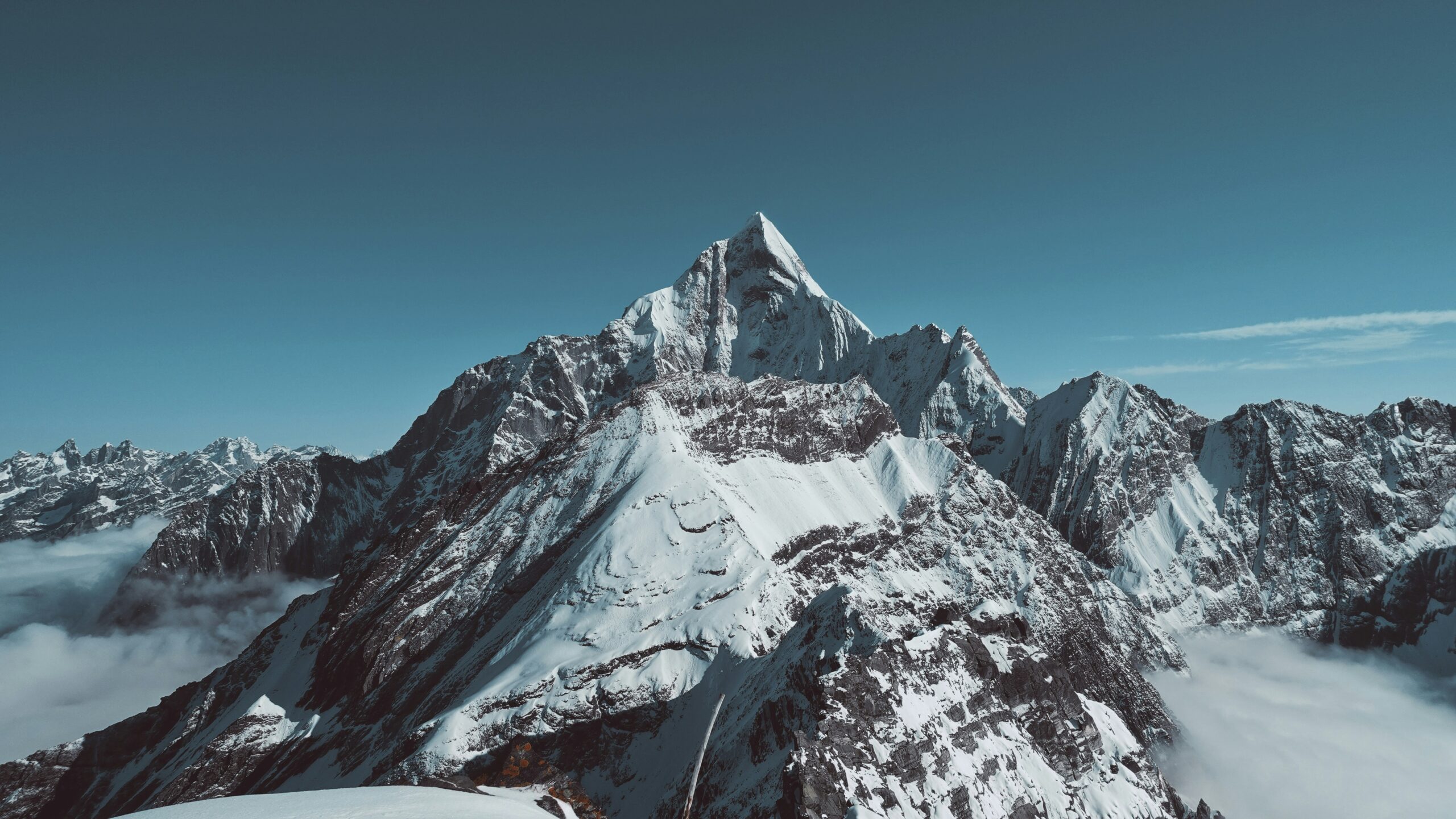 Snow-covered mountain peak rising above clouds under a clear blue sky symbolizing stability and protection against inflation.